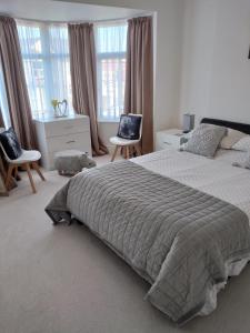 a bedroom with a bed and two chairs and windows at The Golden Sands B&B in Blackpool