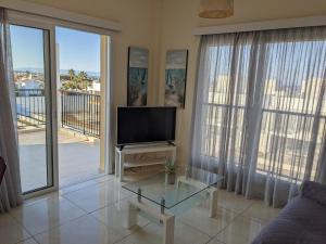 a living room with a flat screen tv and large windows at Adalena Court in Paralimni