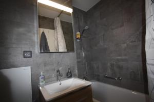 een badkamer met een wastafel, een bad en een spiegel bij Choucas A16 in Crans-Montana