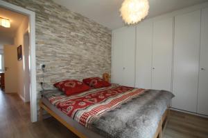 een slaapkamer met een bakstenen muur en een bed met rode kussens bij Choucas A16 in Crans-Montana