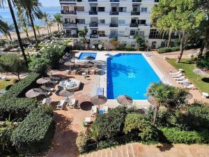 widok na basen z parasolami i hotel w obiekcie Skol 444. Fantastic Renovated 1 Bed Apartment in Skol Marbella w Marbelli
