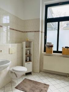 La salle de bains est pourvue de toilettes, d'un lavabo et d'une fenêtre. dans l'établissement Downtown Apartment 4U Leipzig, à Leipzig