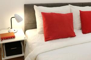 ein Schlafzimmer mit einem Bett mit roten Kissen und einer Lampe in der Unterkunft Apartment Elena Zagreb Center with garage in Zagreb