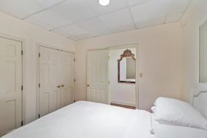 Habitación blanca con cama y espejo en Tranquil Getaway In Gated Community - Free Wifi and laptop-friendly workspace condo, en Cockeysville