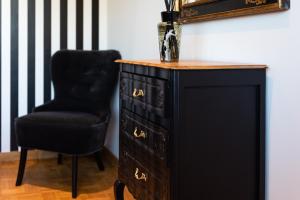 a black dresser with a black chair and a mirror at Cocoon-Chambre d'Hôtes in Namur