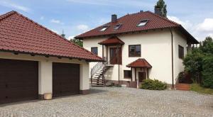 une maison avec deux portes de garage et une allée dans l'établissement Ferienwohnung Oelzschau - Urlaub im Leipziger Neuseenland, à Rötha