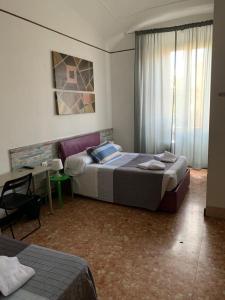 1 dormitorio con 2 camas, escritorio y ventana en Silton's Rooms, en Roma