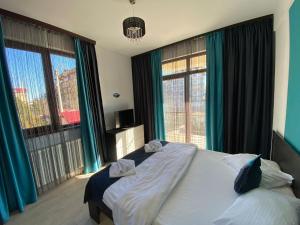a bedroom with a large bed with blue curtains at Apartament Ella T2 in Mamaia Sat/Năvodari