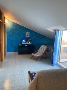 una camera da letto con parete blu, TV e sedia di Casa vacanze costa dei Trabocchi a Fossacesia