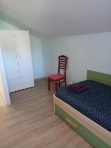 una camera con letto e sedia rossa di Alojamento Local - Casa Amarela ad Alvaiázere