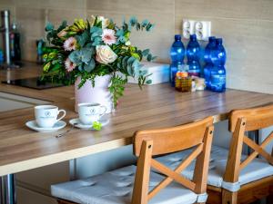 uma mesa com duas cadeiras e um vaso com flores em Słoneczna 10a Apartamenty em Jarosławiec