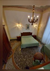 Un dormitorio con una cama verde y una lámpara de araña. en Villa Viola, en Tortona