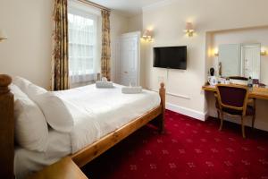 a hotel room with a bed, chair, desk and a television at Bagdale Hall & Annexe in Whitby
