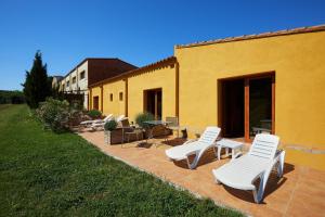 a patio with white chairs and tables and a building at Can Barnosell - Els Masos d'en Coll in Llaviá