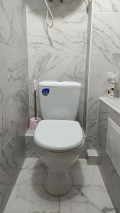 a white toilet in a bathroom with marble walls at Василя Стуса 10/77 City Rooms in Bila Tserkva