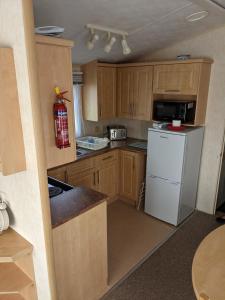 a kitchen with wooden cabinets and a white refrigerator at 8 Berth Northshore (The Westmorland) in Lincolnshire