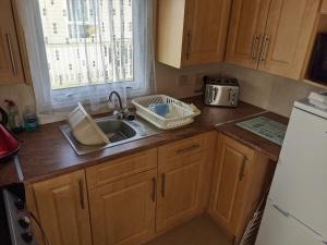 a kitchen with wooden cabinets and a sink and a refrigerator at 8 Berth Northshore (The Westmorland) in Lincolnshire