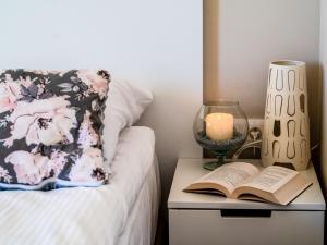 a bed with a book and a candle on a night stand at Słoneczna 10a w Jarosławcu Apartamenty nad morzem in Jarosławiec