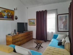 ein Wohnzimmer mit einem Sofa und einem TV in der Unterkunft Ideal for kite surfer&family in Le Morne