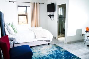 ein Schlafzimmer mit einem weißen Bett und einem blauen Teppich in der Unterkunft Happy Hen Guest Lodge in Bizana
