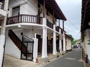 a white building with a balcony on a street at Lighthouse Guest in Galle