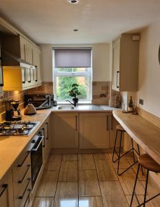 a kitchen with brown cabinets and a sink and a window at Apartment 11, Mirfield, West Yorkshire in Mirfield