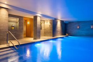 a swimming pool in a hotel with blue lighting at RockyPop Flaine Appartements & Spa in Flaine