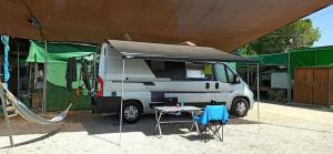 a white caravan parked under a tent with a table at Camping San Javier in San Javier