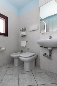 a white bathroom with a sink and a toilet at Hotel Quasar in Cala Liberotto