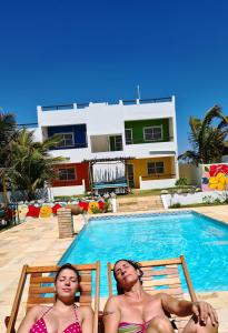 two women laying in chairs by a swimming pool at Pousada lagoa da Barra Taiba in Taíba