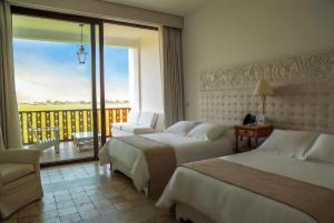 a hotel room with two beds and a balcony at Hotel Viñas Queirolo in Ica