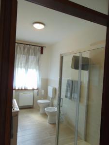 a bathroom with a toilet and a glass shower stall at El gnareto dei nonni in Nove