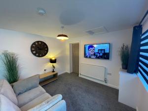 a living room with a couch and a clock on the wall at Serviced Accommodation Moray in Elgin