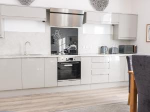 a white kitchen with white cabinets and a sink at 2 Abbey Row in Kelso