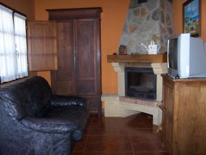 a living room with a leather chair and a fireplace at Casa El Trabeseo in San Martín de Luiña