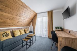 een hotelkamer met een bank en een tv bij Janosówka in Czarna Góra