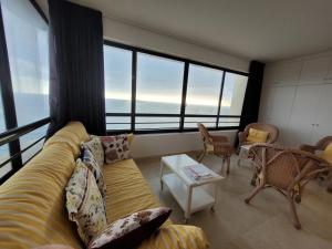 sala de estar con sofá, sillas y ventanas en Torre Levante-Fincas Benidorm, en Benidorm