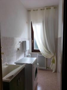 a bathroom with a washing machine next to a tub at Casa Degli Ulivi in Lazise