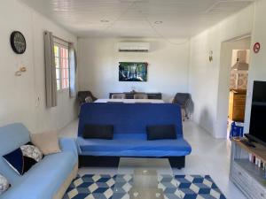 sala de estar con sofá azul y cama en Gite les Bananiers, en Saint-Joseph