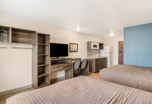 a hotel room with two beds and a desk with a television at WoodSpring Suites Thornton-North Denver in Thornton