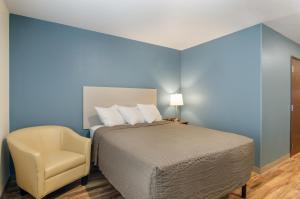 1 dormitorio con 1 cama y 1 silla en WoodSpring Suites Thornton-North Denver, en Thornton