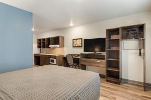 a bedroom with a bed and a desk with a television at WoodSpring Suites Thornton-North Denver in Thornton