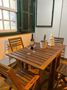 un tavolo in legno con 2 bicchieri e una bottiglia di vino di Primera línea en piscinas naturales. a Barlovento