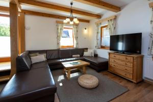a living room with a leather couch and a flat screen tv at Chalet Pr Dobravc in Bohinj