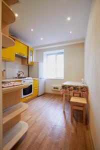 a kitchen with yellow cabinets and a table in it at Vilenskaja 25 in Maladzyechna