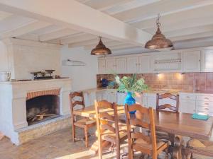 a kitchen with a wooden table and a fireplace at Château Bégot in Lansac