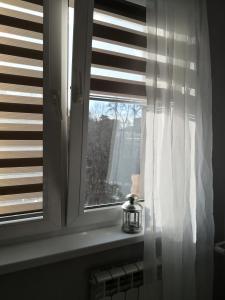 uma janela com uma cortina branca e uma vela em Różowe sny em Klodzko