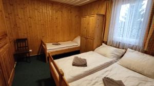 Habitación pequeña con 2 camas y ventana en Penzion apartmány Aninka en Mariánská