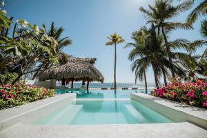 a pool at the beach with palm trees and flowers at Villa Rincon del Mar & Villa Rincon de las Morenas in Coyuca