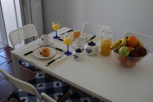 a table with a breakfast of fruit and orange juice at Murtosa House in Torreira